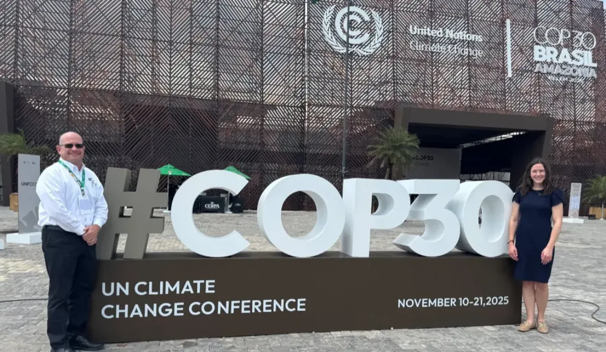 Man and woman standing in front of large white letters spelling COP30 and a sign below that reads UN CLIMATE CHANGE CONFERENCE NOVEMBER 10-21, 2025. The man is Jamie Burr and the woman is pig farmer Madison Hokanson, representing U.S. Pork at the conference venue in Bélem, Brazil.